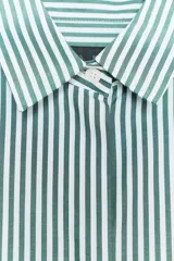 Camisa de mujer con cuello solapa y manga tres cuartos con estampado a rayas verticales verdes y blancas. Cierre frontal con botones ocultos.