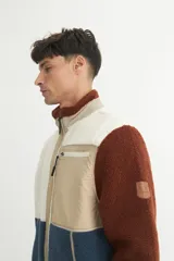Campera de sherpa doble faz en tonos marrón, beige y azul, con cierre frontal y bolsillos laterales.