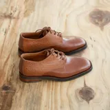 Zapato acordonado de cuero color marrón con detalle de textura reptil en el talón y empeine. Taco de madera foliado en cuero de 2,5 cm de altura y entre suela de goma de 1 cm.