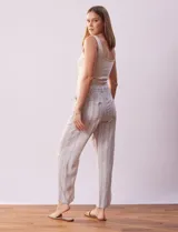 Pantalón largo de lino y rayón a rayas verticales grises y blancas. Tiene pretina elastizada con lazo de ajuste, bolsillos delanteros y traseros.
