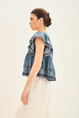 Camisa celeste de corte amplio confeccionada en tencel, con mangas cortas y ruedo con terminación de volado.