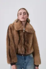 Campera de piel sintética color tostado con cuello clásico, cierre frontal de cremallera y terminaciones elásticas en puños y cintura.