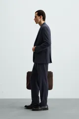 Pantalón de vestir azul marino, de corte slim fit, confeccionado en tejido con 17% de lana. Cuenta con bolsillos frontales y traseros de doble vivo con botón. Cierre frontal con cremallera y botón.