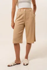 Bermuda color beige de corte ancho, con cintura alta, botón y bolsillos laterales.