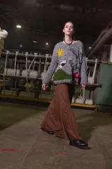 Sweater tejido de lana color gris con cuello redondo y puños acanalados. Presenta un diseño bordado a mano con motivos campestres: sol, vaca, árbol y granero.