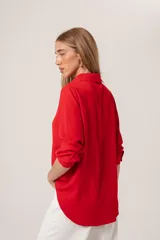 Camisa clásica roja confeccionada en tela ligera tipo gasa, de tacto suave y caída fluida, con cuello clásico y cierre frontal con botones.