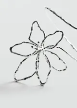 Brazalete plateado con forma de espiral y diseño de flor calada.