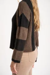 Sweater de tejido de punto grueso, con diseño de rayas verticales anchas en tonos marrón oscuro y negro. Presenta cuello redondo y mangas largas.