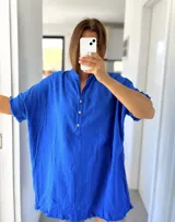 Túnica azul de lino rústico con cuello mao y botones. Tiene mangas cortas y ruedo con flecos.