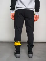 Pantalón de jogging negro con cordones amarillos, puños ajustados y escudo del Club Atlético Peñarol bordado en amarillo.