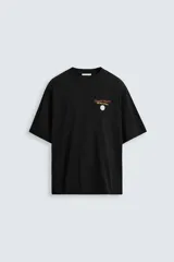 Camiseta negra de corte relajado, cuello redondo y manga corta. Presenta estampado frontal con la frase "Comfort Food!!! Our Daily Specials" y un dibujo de una flor.