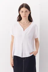 Blusa blanca de lino con escote en V y mangas cortas.