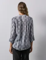 Blusa de gasa estampada con cuello a la base, escote en V y abertura central con botones. Delantera con plisados y mangas 3/4 regulables con presilla y botón.