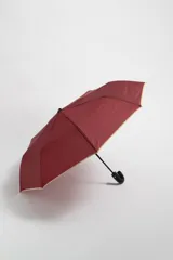 Paraguas color bordó con estructura de metal y mango ergonómico.