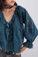 Camisa blanca de algodón con detalles de plumetí, puntillas, alforzas y bordados a tono. Tiene volados en el frente y mangas al codo abullonadas con elástico y volados.
