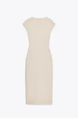 Vestido midi color beige confeccionado en hilatura con algodón. Tiene cuello redondo, manga corta caída y detalle de drapeado lateral.