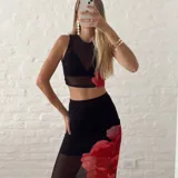 Conjunto de top corto y falda larga de tul negro con estampado de flores rojas.