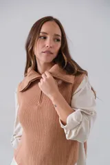 Chaleco de punto color camel, con cuello alto, medio cierre frontal y botones decorativos en los laterales.