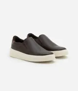 Championes slip on de cuero color marrón oscuro con detalle de cuero marrón claro en el talón y suela de goma color crema.