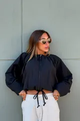 Campera negra corta con frunces en la cintura y cierre frontal.