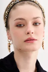 Aros colgantes dorados con forma de argolla pequeña y dije en forma de cuerno de resina con incrustaciones de strass.