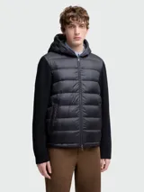 Campera Moncler con cuerpo acolchado negro, mangas largas de punto de lana negra y capucha con cordón ajustable. Cierre frontal con cremallera y bolsillos laterales con cremallera.
