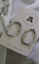 Aros colgantes plateados con forma ovalada irregular y apliques de strass.