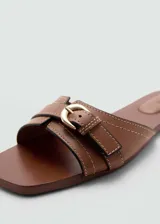 Sandalias planas color marrón cuero, con punta cuadrada, diseño de tiras y hebilla decorativa.