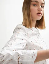 Camisa blanca de manga larga con tejido broderie (ojales bordados) y cuello camisero.