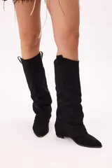 Botas de caña alta color negro, estilo texanas, confeccionadas en símil gamuza con efecto slouchy, punta afinada y suela cómoda.