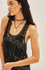 Vestido corto negro de tul bordado con piedras, lentejuelas, canutillos y flecos de mostacillas. Tiene escote redondo, calce recto y viso a tono con breteles finitos.