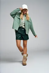 Camisa verde de pana con corte oversize, cuello clásico, hombros caídos, bolsillos frontales con solapa y cierre de botones.