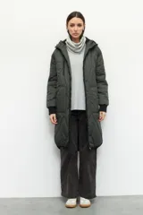 Campera larga oversized color verde militar, de nylon capitoneado con interior de polar y puños ajustados. Tiene capucha, tres bolsillos externos y uno interno.