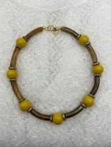 Collar corto con cuentas redondas color lila y cuentas cilíndricas color verde oliva, separadas por anillos dorados.