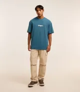 Remera relaxed azul petróleo de algodón, con cuello redondo en rib, manga corta y estampa localizada en relieve con la palabra "Eternal".