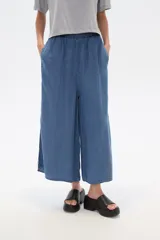 Pantalón capri de denim azul con cintura elástica y aberturas laterales en el ruedo.