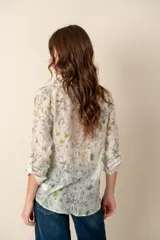 Camisa celeste con estampado de soles, lunas, flores y tortugas en tonos verdes, amarillos y naranjas.