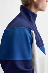 Chaqueta deportiva azul marino, azul y blanca con cierre frontal, cuello alto y bolsillos laterales.