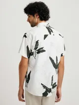 Camisa blanca de manga corta con estampado de hojas en negro y gris, cuello clásico y corte recto.