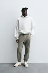 Pantalón jogger negro de corte slim fit, confeccionado en tejido de algodón con cintura elástica ajustable con cordón, bolsillos frontales y traseros de vivo, y bajo con puño elástico.