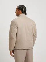 Campera acolchada reversible, color negro con interior beige, cuello mao y cierre frontal con cremallera.