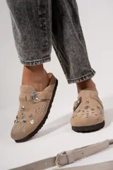 Suecos de cuero gamuzado color beige, con apliques metálicos y hebilla decorativa.