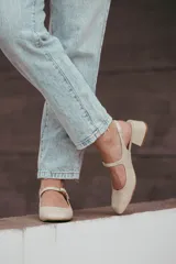 Zapatos estilo Mary Jane color beige, confeccionados en cuero, con taco cuadrado de 6 cm y tira con hebilla sobre el empeine.