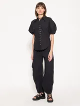 Camisa negra de popelina, de silueta amplia y diseño liviano. Incluye cuello clásico y cierre frontal con botones.