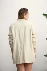 Blazer celeste de lino con solapas de muesca, cierre cruzado con botones, bolsillos delanteros con solapa y corte holgado.