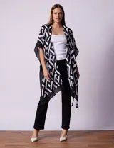 Kimono tejido con estampado geométrico en blanco y negro, ruedo con borlas y composición 100% poliéster.