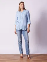 Camisa celeste con rayas verticales blancas, de corte recto y manga 3/4 regulable con presilla y botón.