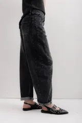 Pantalón de jean negro con corte amplio y ruedo doblado.