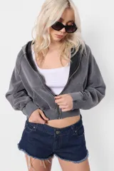 Campera gris de frisa con lavado acid, silueta oversize, manga ranglan con recortes verticales, puños de frisa con recortes de rib y mitones, cintura de rib al tono, capucha forrada al tono en su interior y bolsillo canguro. Acceso frontal mediante cierre desmontable metálico YKK con tiracierre personalizado con logo de marca.