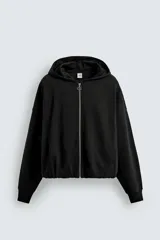 Sudadera negra con capucha, corte boxy, cierre frontal con cremallera, bolsillos laterales y puños elásticos.